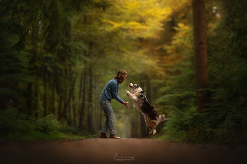 Charlotte Olsthoorn, eigenaresse van holistische praktijk voor dieren, met haar Australian Shepherd Liv springend in het bos